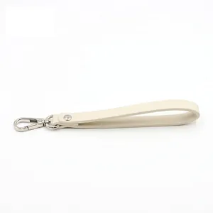 Detail of cream crossgrain PU leather wristlet strap with silver lobster clasp and neat stitching