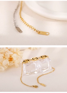 Macro detail of K14 gold plated hollow bracelet with engraved metal tag on beige surface