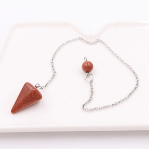 Brown goldstone pendulum pendant on silver chain displayed on white ceramic tray