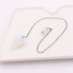 Macro shot of white opal cone pendant with silver chain on elegant ceramic tray