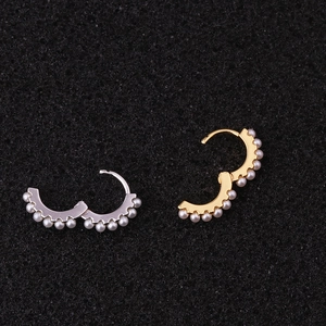 Close-up of gold and silver hoop earrings featuring minimalist inlaid white pearls