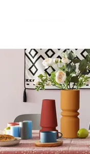 Detail van matte keramische vazen in steenrood en geel met moderne geometrische vormen