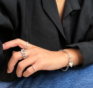 Close-up of 925 sterling silver heart charm bracelet and stacked rings on a model