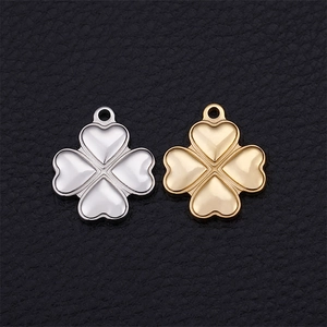 Golden and silver metal heart four-leaf clover charms on black leather background