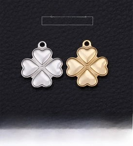 Detailed view of gold and silver four-leaf clover charms on black leather background