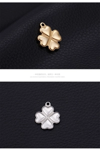 Detail of four-leaf clover heart pendants in gold and silver with white shell inlay