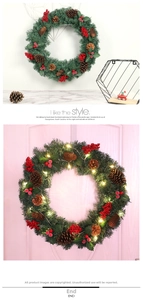 Detail of Christmas wreath with pine needles, red berries, cones and warm LED lights
