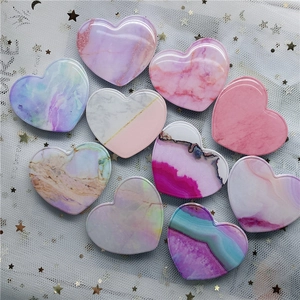 Flat lay of heart-shaped marble phone grips in various pastel patterns on starry mesh cloth