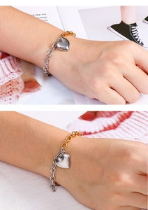 Détail d'un bracelet bicolore or et argent avec pendentif cœur au poignet
