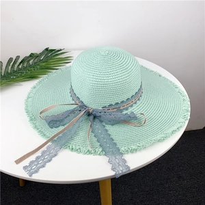 Light green woven straw sun hat with frayed brim and delicate blue lace ribbon ties