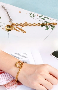 Detail of two-tone gold and silver chain bracelet with hollow heart pendant on wrist