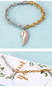 Détail macro du bracelet bicolore en acier avec pendentif plume argentée et fermoir mousqueton