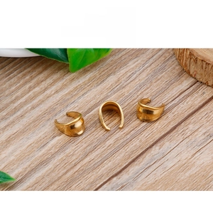 Macro shot of three golden U-shaped jewelry clasps on a rustic wooden background