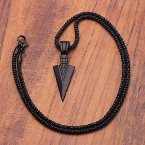 Detailed view of a vintage black arrow pendant necklace on a rustic wooden background