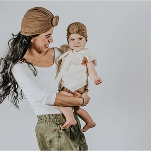 Close-up of mother and baby matching knit donut turban hats in dark caramel