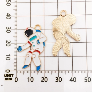 Detailed macro view of enamel astronaut pendants showing front design and golden textured back