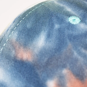 Close-up of tie-dye cotton twill fabric with breathable eyelet and stitching details