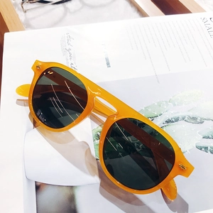 Detail of orange resin frame sunglasses with dark lenses on a magazine background