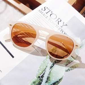 Beige sunglasses with orange lenses placed on a lifestyle magazine with cactus background