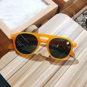 Trendy orange round frame sunglasses with dark lenses on a wooden stand for men and women