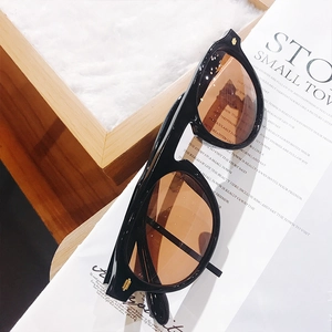 Classic black frame sunglasses with amber lenses displayed on a magazine and fur surface