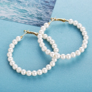 Classic oversized hoop earrings with white pearls and gold clasp on blue background