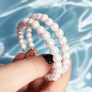 Detail of hoop earrings with white round pearls and a textured gold-tone metal base