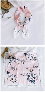 Detail of pink and white floral silk square scarf tied on a straw bag with smooth texture