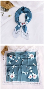 Detailed view of teal silk square scarf with elegant white floral patterns and satin gloss