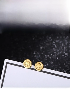 Macro detail of golden octagonal Tree of Life stud earrings with embossed texture