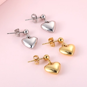 Orecchini a cuore in acciaio al titanio color oro e argento su sfondo rosa