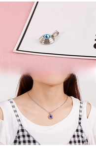 Detail of silver round pendant with blue zircon stone shown on a model