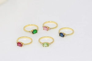 Detailed view of five gold plated rings set with colorful oval cut zircon gemstones