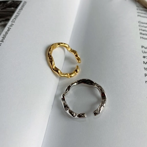 Close-up of gold and silver irregular lava texture S925 silver rings on a book