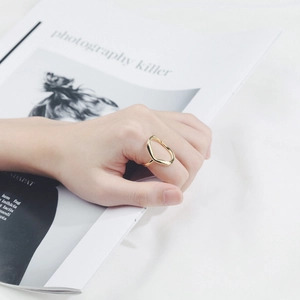 Irregular geometric open ring in gold plated finish worn over a magazine background