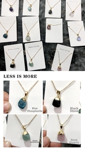 Detailed view of raw natural stone pendants including rose quartz on a display card