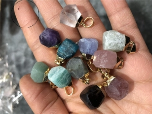 Close-up of assorted natural crystal stone pendants with gold metal bails held in hand