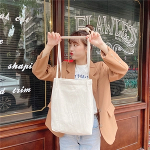 Detailed texture of white cotton linen tote bag on model in casual urban setting