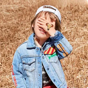 Detail of blue denim jacket for kids with red video game lettering and vintage cowboy style