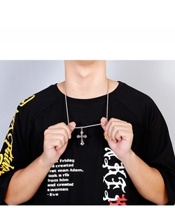 Detail of vintage embossed cross pendant in silver stainless steel on male model