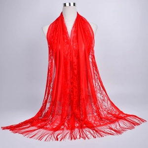 Macro detail of red lace shawl with intricate hollow patterns and fringe hem decoration
