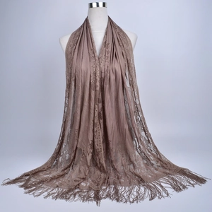 Detail of tan lace shawl with hollow floral patterns and long fringe tassels