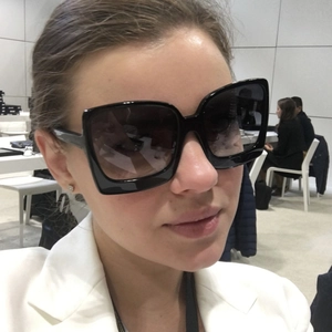 Detail of oversized black square sunglasses featuring thick frames and dark gradient lenses