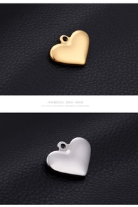 Polished gold and silver heart-shaped pendant charms on a black leather texture