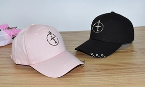 Detail view of pink and black baseball caps featuring metal rings and airplane charms