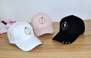 Close-up of baseball caps in white, pink and black with metal rings and number 5 charms