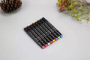 Flat lay of eight dual-tip colorful art markers with pine cones on a grey background