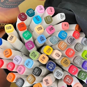 Close-up of colored alcohol markers with numbered caps in a black storage case