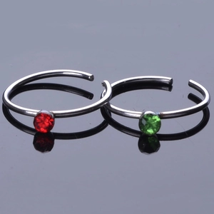 Detailed close-up of C-shaped stainless steel nose rings with red and green crystals