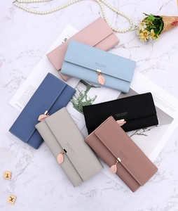 Flat lay of colorful long wallets with leaf pendants on marble background with pearls